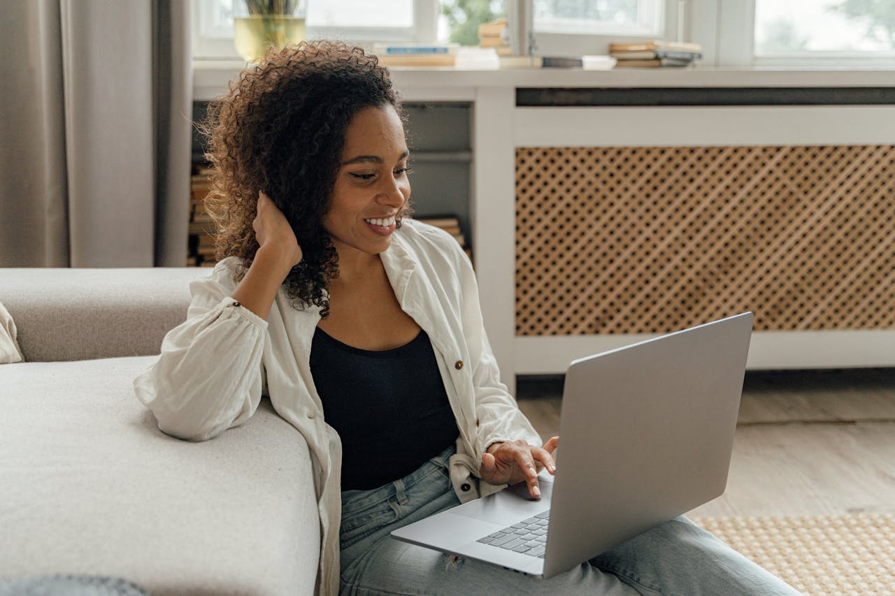 Smiling woman working from home on a laptop in a cozy living room setting.